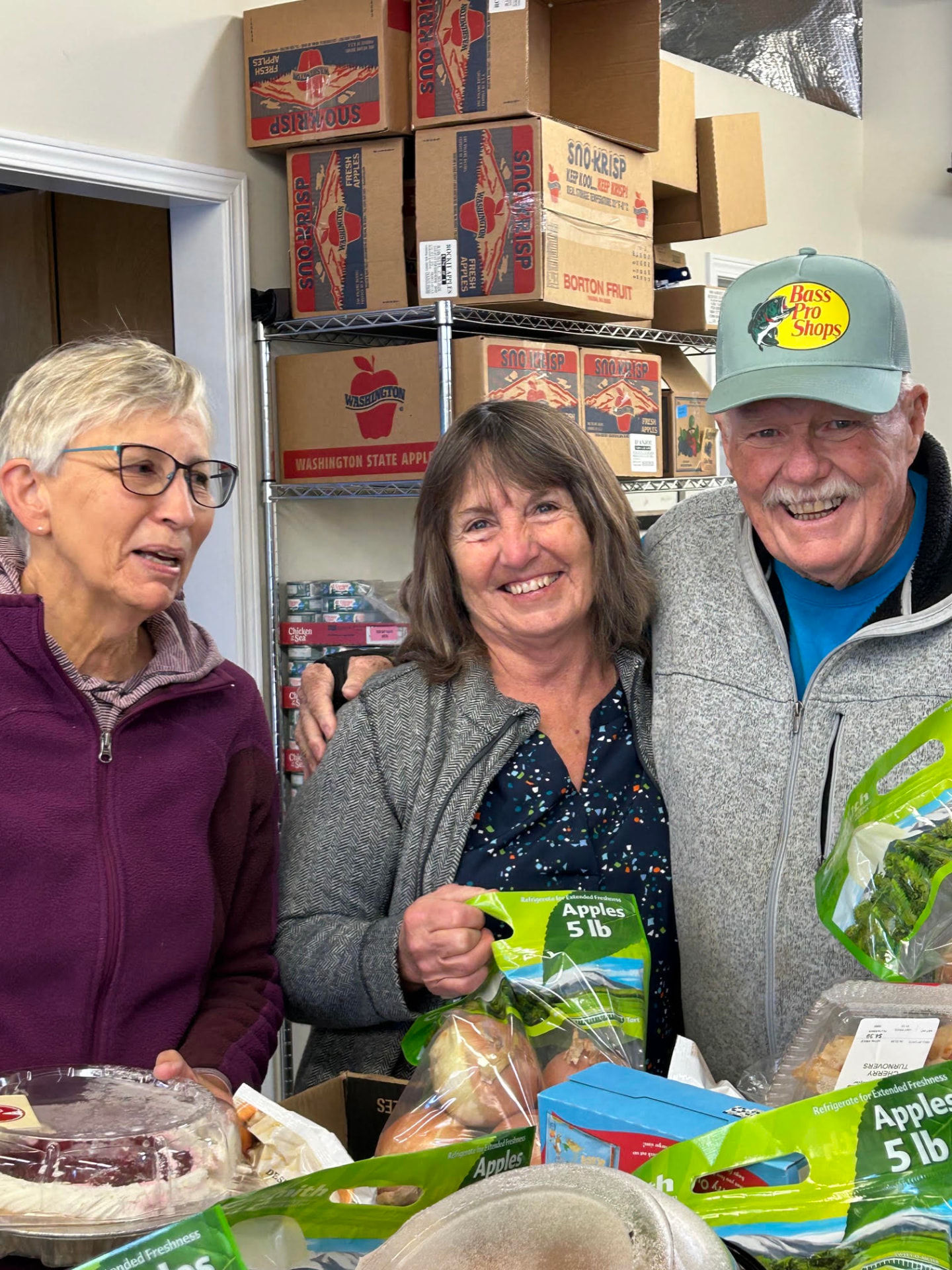 Volunteers laughing together while packing bags of Washington apples
