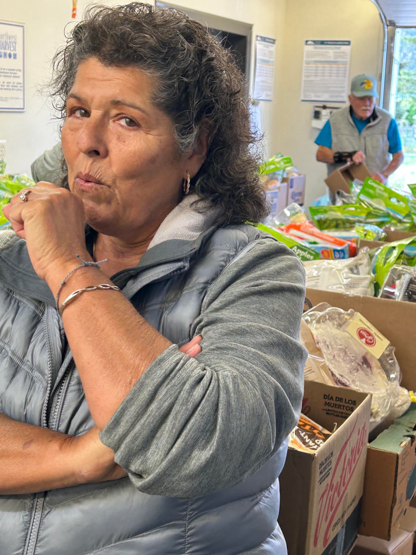 A volunteer sorting groceries while another loads boxes in the background